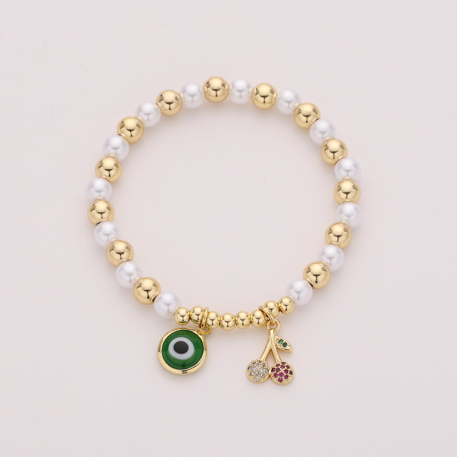 ELASTICO PERLAS Y BOLAS DORADAS / DIJE CEREZA Y OJO / DORADO